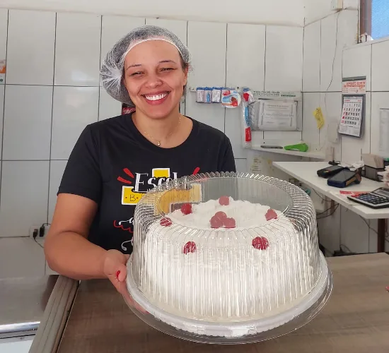 Atendente da Dona Maria com bolo confeitado no balcão